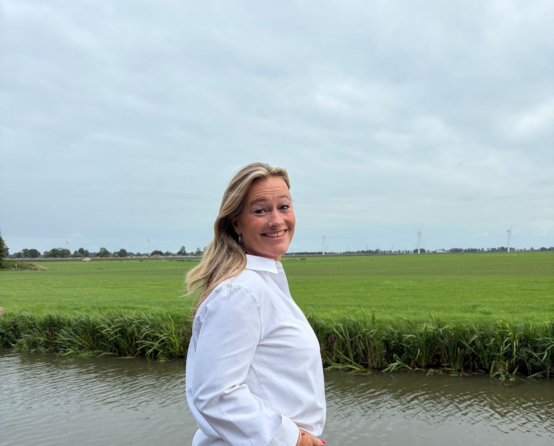 Mirella Beckers-Flantua bij het water, met weiland op de achtergrond